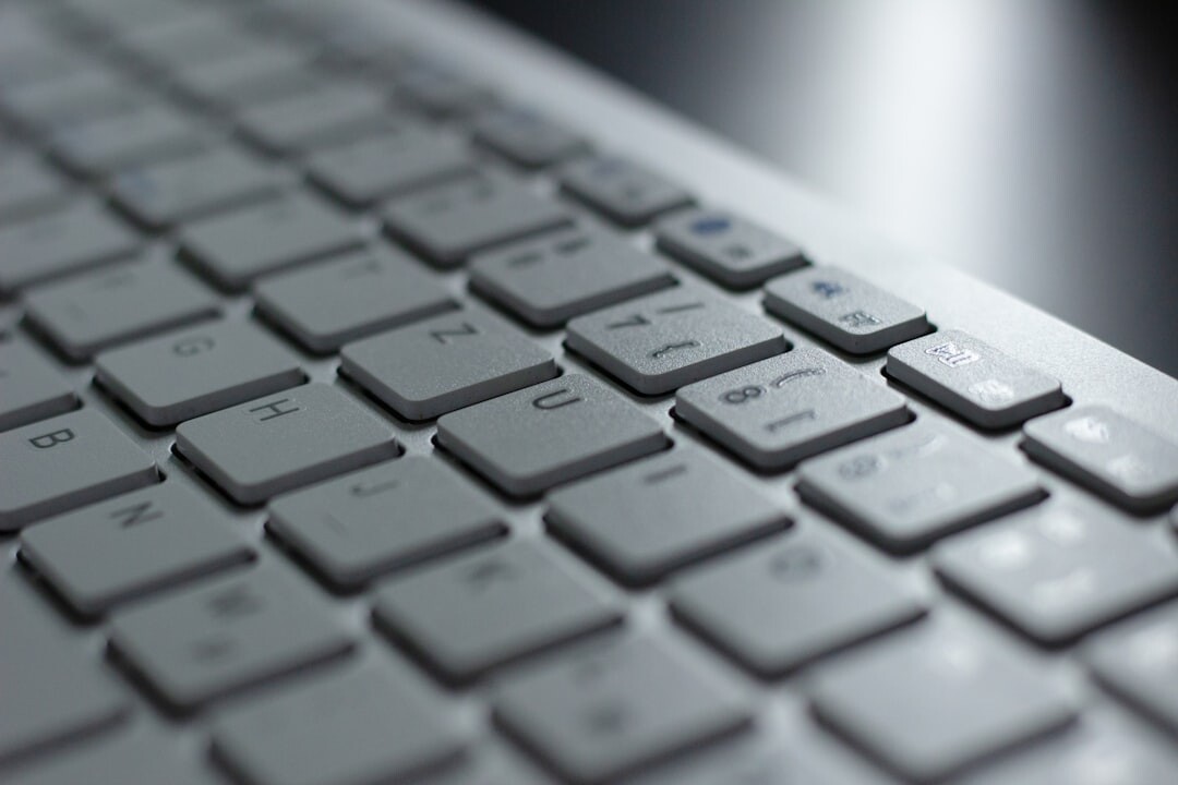 Close-up of hands typing on a laptop keyboard at a desk